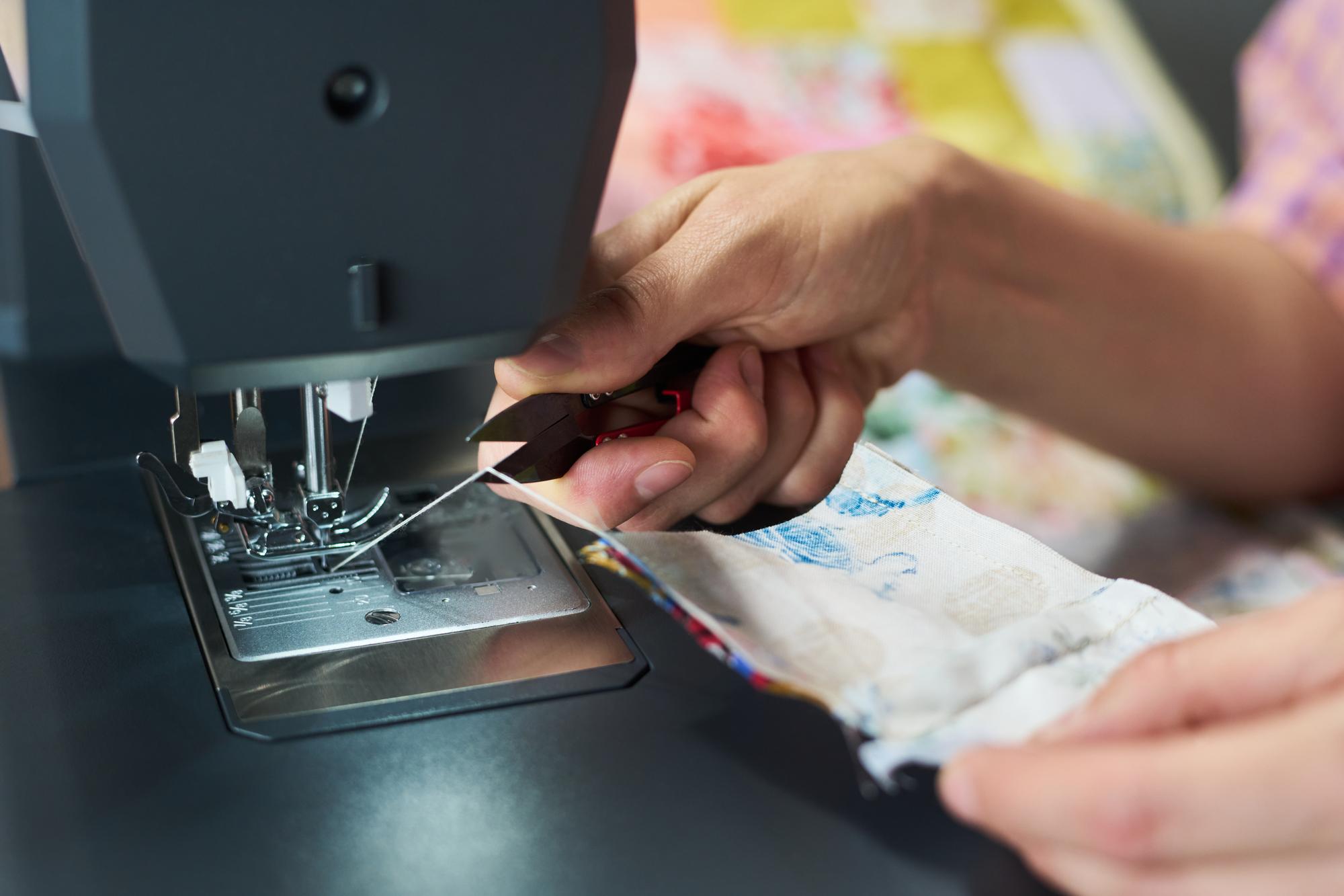 artist hand guiding fabric under embroidery machine